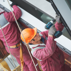 Commercial Window Installation, Two builders worker installing glass windows on facade of business building