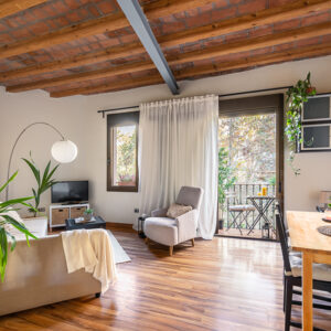 Window Remodeling Service for Open-Concept Homes Connecting Indoor and Outdoor Spaces, Cozy living area with wood-beamed ceiling with dining table sofas and TV with potted palm tree overlooking the open balcony door. Mediterranean house interior concept