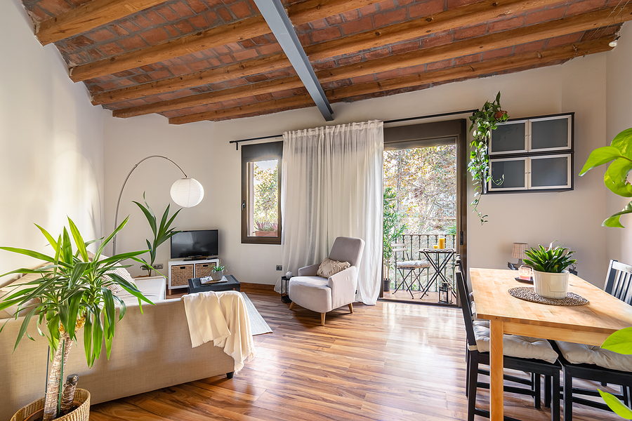 Window Remodeling Service for Open-Concept Homes Connecting Indoor and Outdoor Spaces, Cozy living area with wood-beamed ceiling with dining table sofas and TV with potted palm tree overlooking the open balcony door. Mediterranean house interior concept